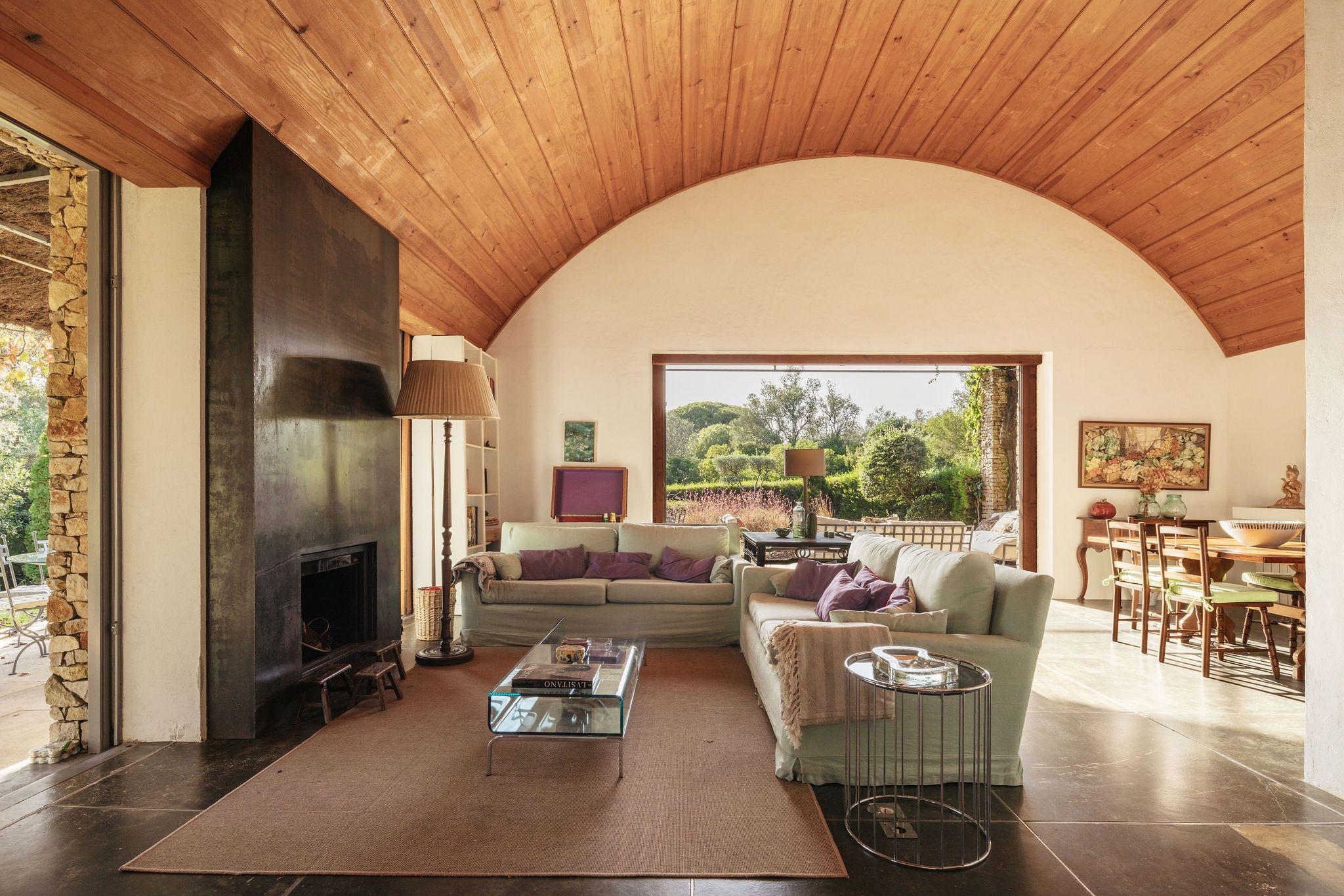 Una sala de estar acogedora con chimenea, un sofá, una mesa de centro y una zona de comedor con sillas y una mesa.