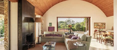 Una sala de estar acogedora con chimenea, un sofá, una mesa de centro y una zona de comedor con sillas y una mesa.