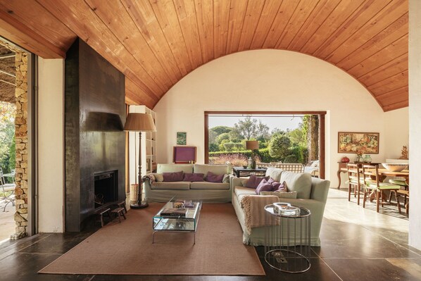 A cozy living room with a fireplace, a sofa, a coffee table, and a dining area with chairs and a table.