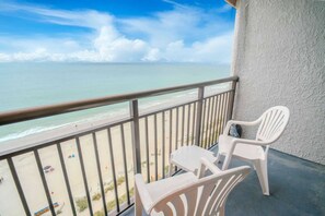 A balcony with a view of the beach and ocean.
