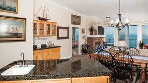 A kitchen with granite countertops, wooden cabinets, and a dining area with a table and chairs.