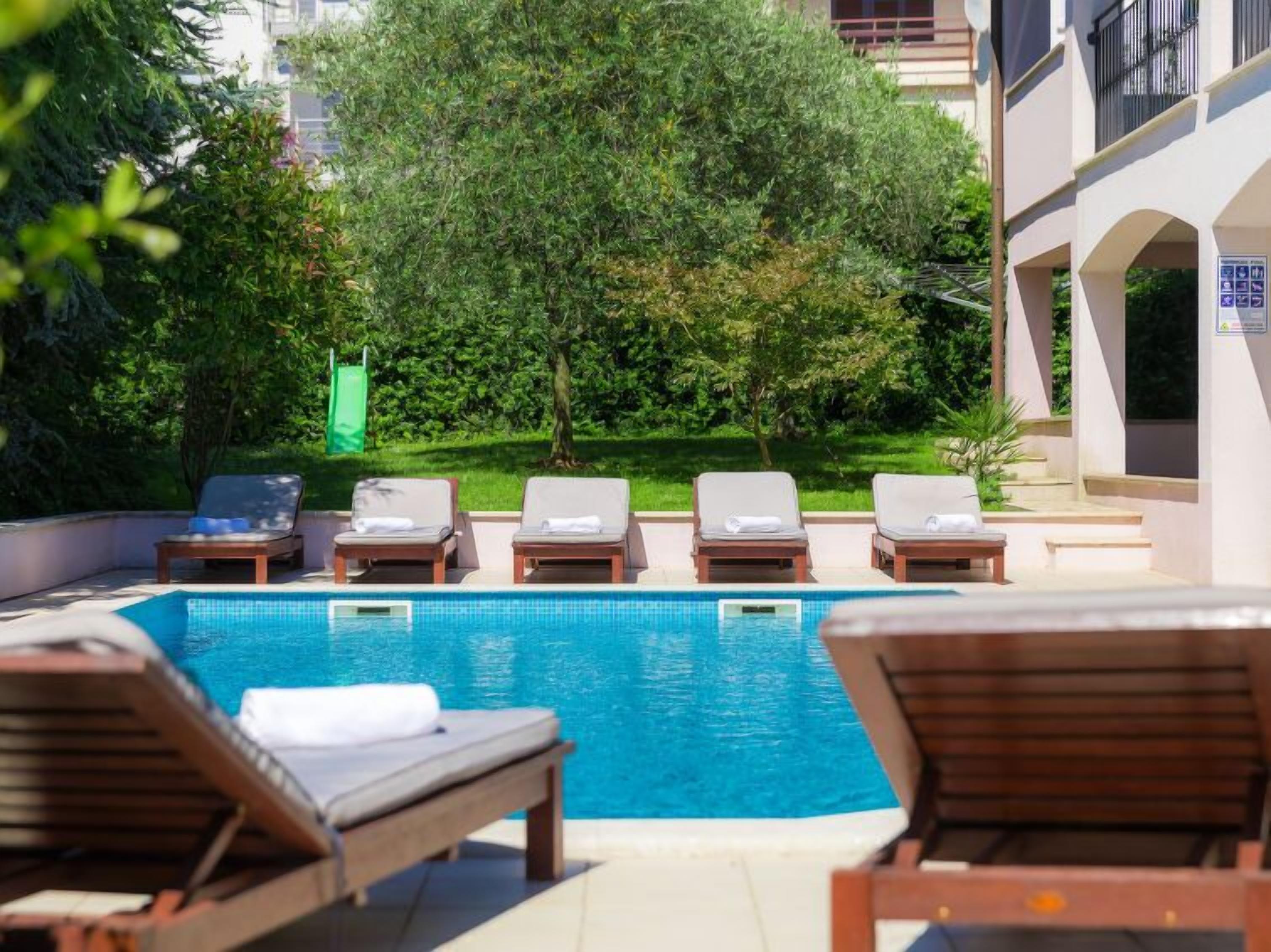 A pool area with lounge chairs and a clear blue pool.