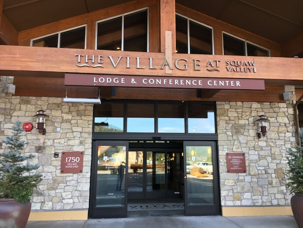 Enter The Village at Squaw Valley through the charming entrance, flanked by lush greenery.