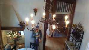 A dining area with a chandelier, a table, and chairs. There is a staircase in the background leading to an upper level. - Unusual, Charming 16th Century Apt Near Place Des Vosges (Paris)
