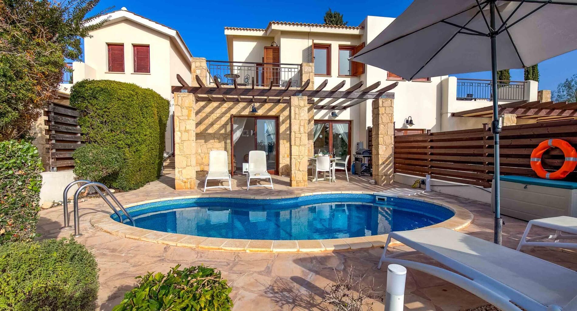 A swimming pool with lounge chairs, a pergola, and a lifebuoy.
