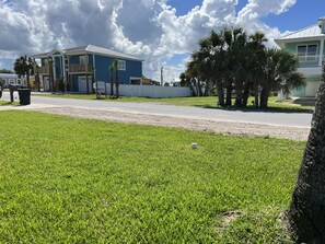 A residential area with a blue house, a white fence, and palm trees.