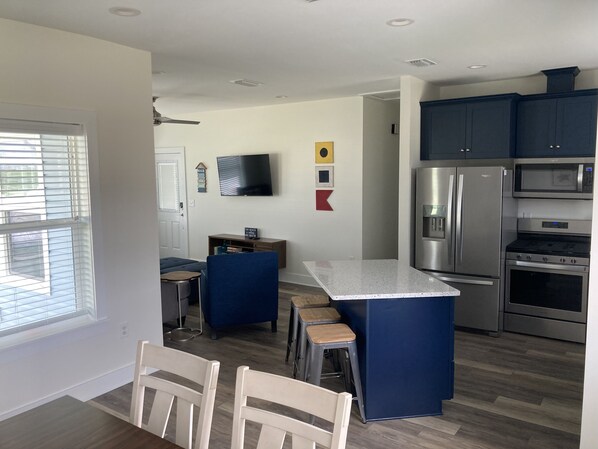 A modern kitchen with a central island, stainless steel appliances, and blue cabinetry.