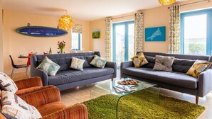 Een moderne woonkamer met twee banken, een glazen salontafel en een eethoek met een tafel en stoelen.