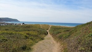 Een kustpad dat naar de zee leidt, onder een heldere lucht.