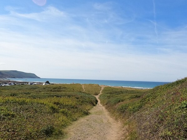 Un camí costaner que condueix al mar sota un cel serè.