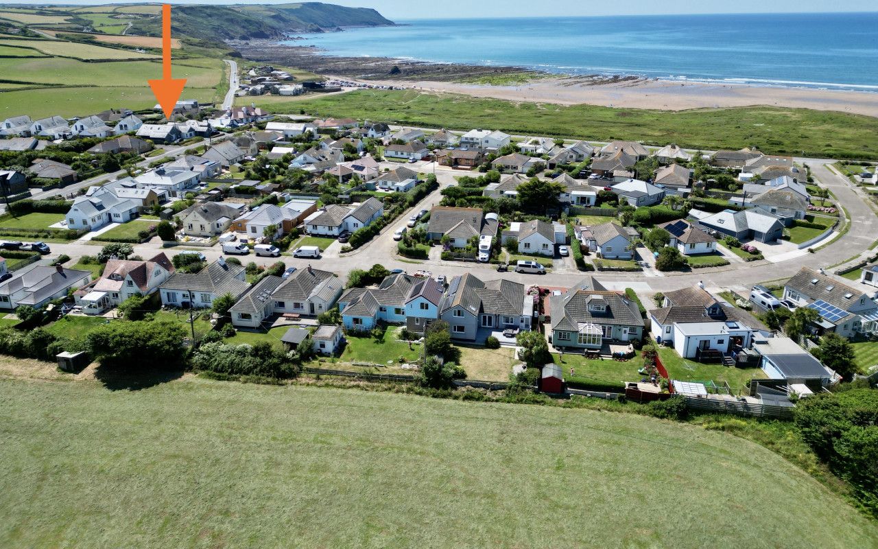 A residential area with houses and a road leading to a beach.