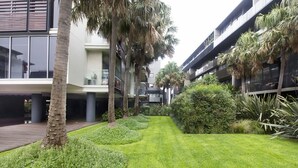 A modern building with a courtyard featuring palm trees and well-maintained grass. - 250m from the beach.Gym/lap pool access,Parking, pet friendly, outdoor area, BBQ (Port Melbourne)
