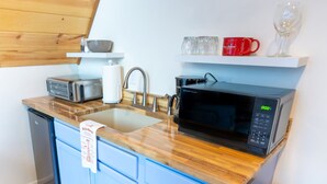 A compact kitchen with a microwave, toaster, and sink.
