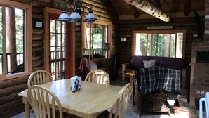 L’intérieur d’une cabane en rondins, avec une table à manger, des chaises, un canapé et une cheminée.