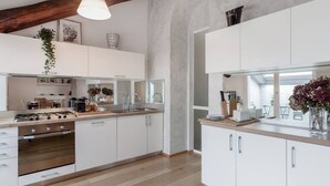 Una cocina moderna con armarios blancos, estufa a gas y encimera de madera.