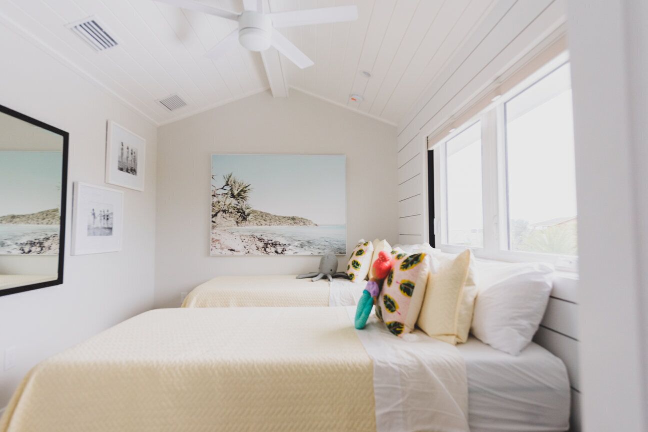 Ein Schlafzimmer mit zwei Betten, einem Deckenventilator und Bildern an den Wänden.