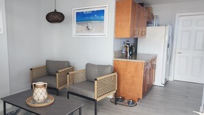 Ett vardagsrum med en soffa, ett soffbord, en dekorativ vas och en inramad tavla på väggen.