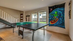 Una stanza con tavolo da ping pong, una scala e un grande arazzo a tema spaziale appeso al muro.
