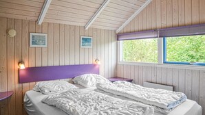 A room with wooden walls, a bed with white bedding, two bedside tables, and a window with a view of greenery. - Gorgeous home in Hemmet with sauna (Hemmet)