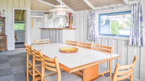A dining area with a white table, six wooden chairs, and a central woven basket. - Gorgeous home in Hemmet with sauna (Hemmet)