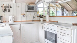 A kitchen with white cabinetry, a microwave, a kettle, and a stove. - Gorgeous home in Hemmet with sauna (Hemmet)