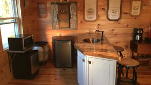 A compact kitchen with a microwave, refrigerator, sink, and bar stool. - THE HAY LOFT in the Beautiful Shenandoah Valley (Mt Jackson)