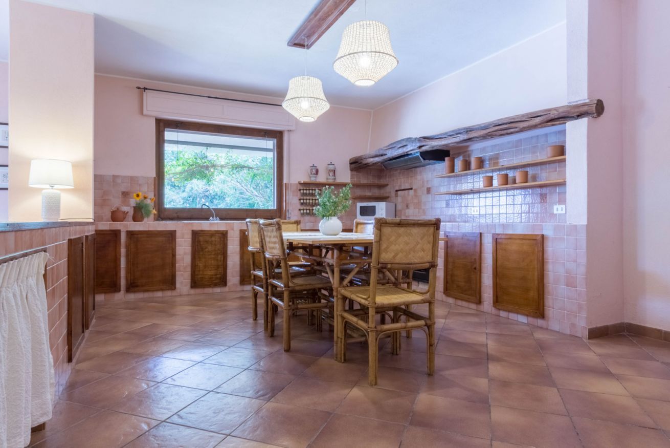 A kitchen with a dining table, chairs, and hanging light fixtures.