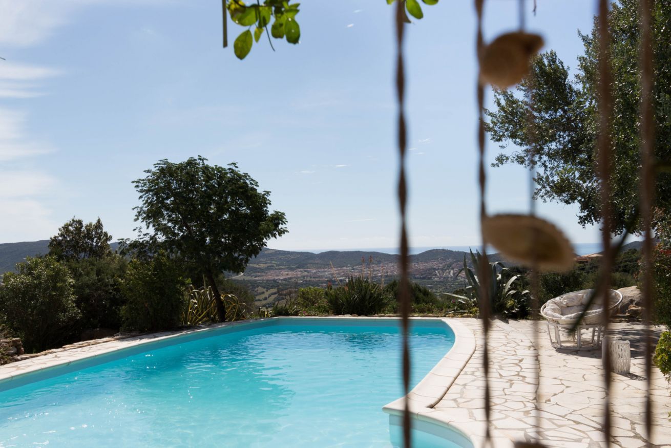 A pool with a clear view of the landscape, surrounded by greenery and a stone patio.