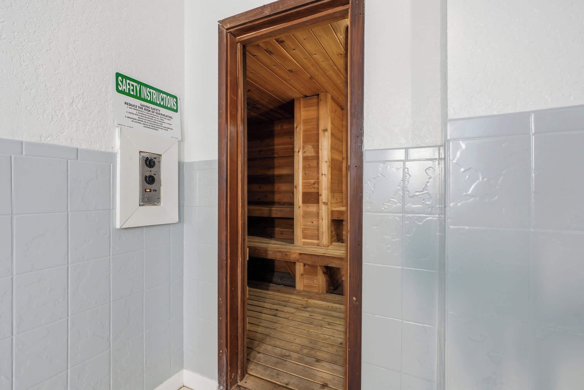 A bathroom with a wooden door, a safety instruction sign, and a wall-mounted thermostat.