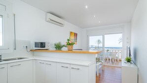 Une cuisine moderne avec des meubles blancs, un four à micro-ondes et un petit îlot central agrémenté d’une plante.