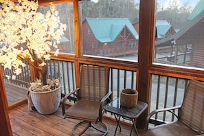 Relax on the cabin's deck, surrounded by lush greenery and a charming potted tree.