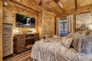 Relax in a warm, inviting space with a plush bed, fireplace, and wooden beams.