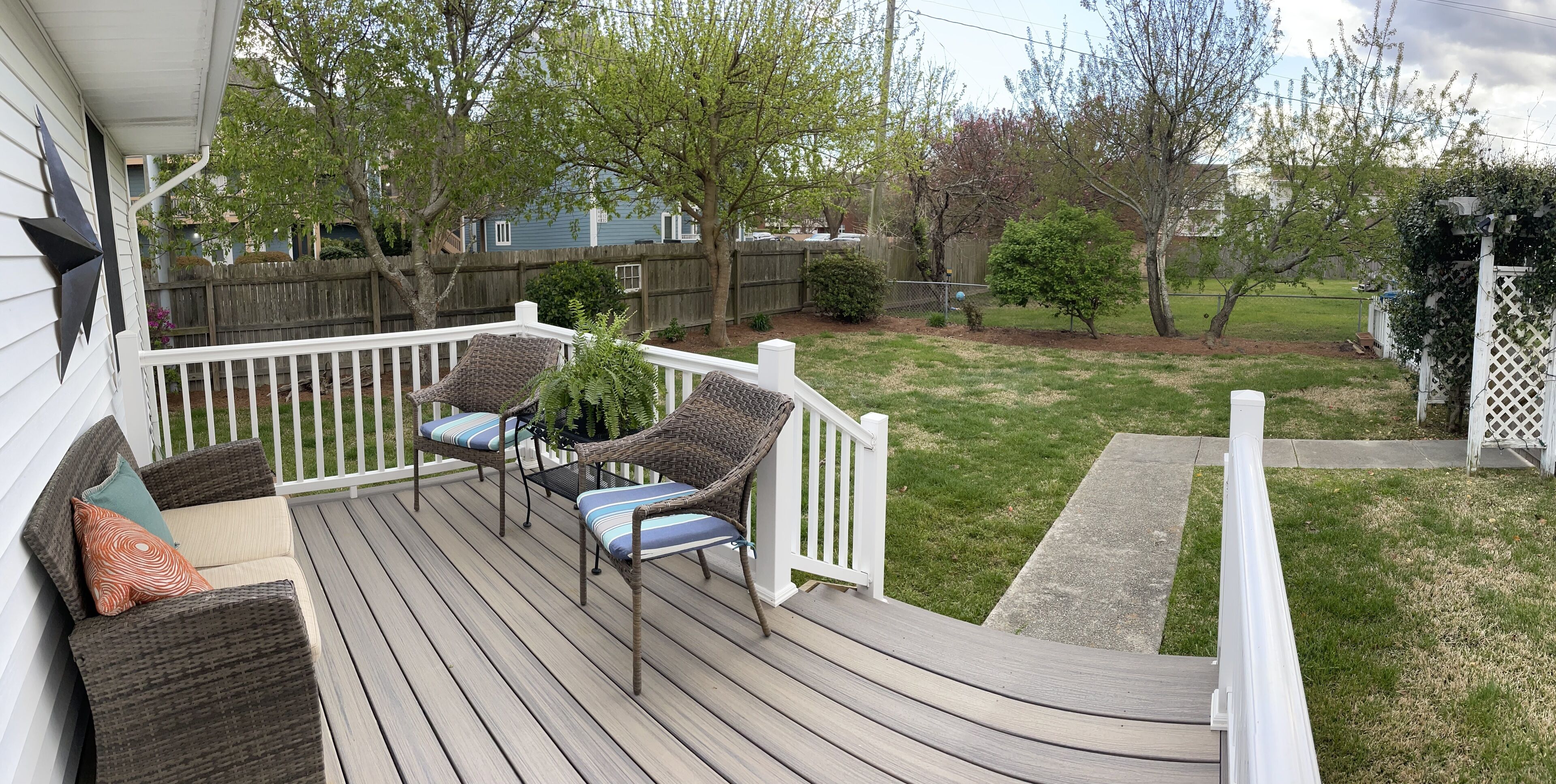 A wooden deck with wicker furniture and a white railing.