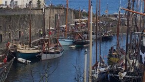 En havn med flere både i havnen, en murstensbygning og udsigt til havet.