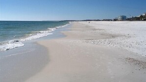 A beach with a clear sky, calm sea, and a long stretch of sand. - The Club at Mexico Beach - Our Happy Place (Mexico Beach)