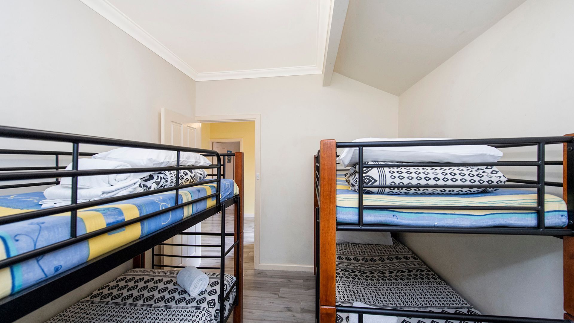 A corridor with bunk beds, each with patterned bedding and pillows.