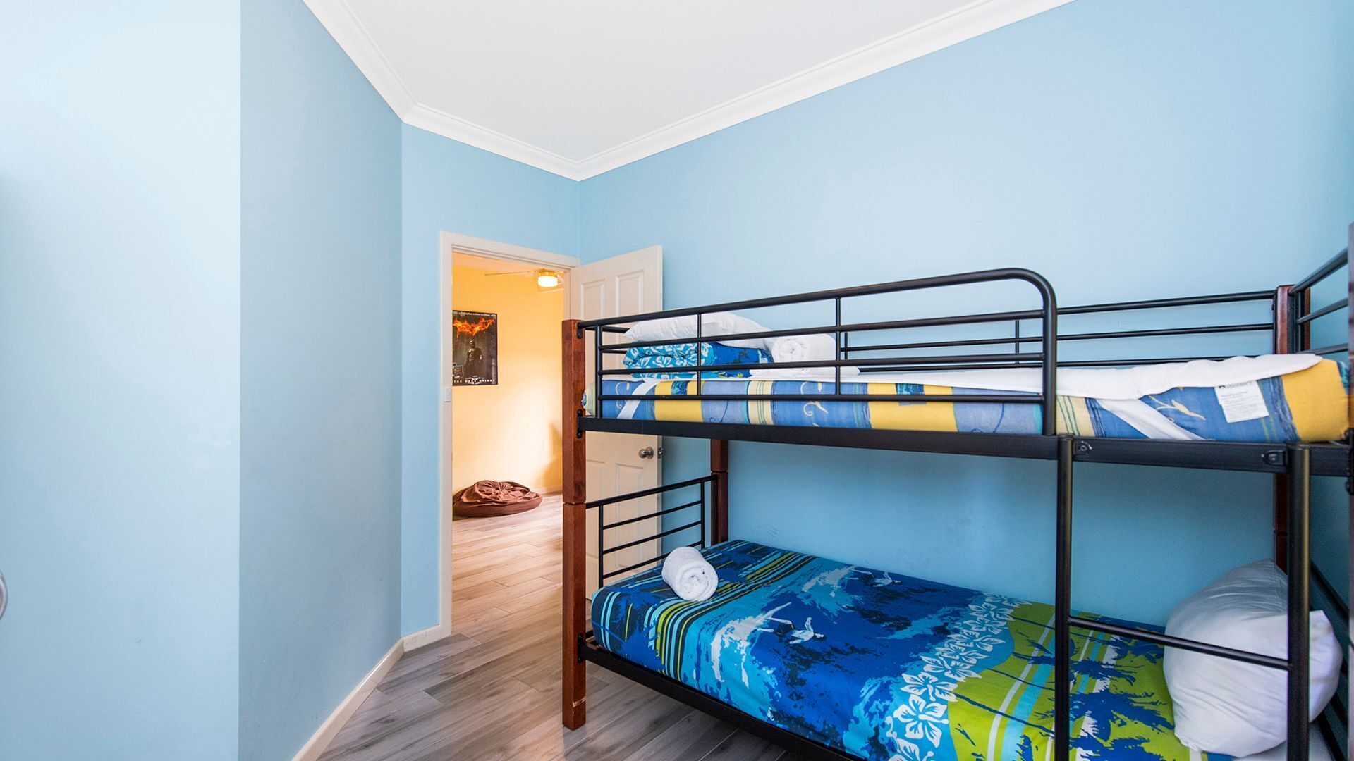 A bunk bed room with blue walls and wooden flooring.