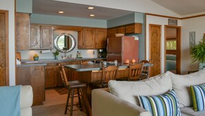 Keittiössä on puiset kaapit, jääkaappi ja ruokailutila, jossa on tuoleja.
