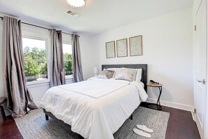 Ein Schlafzimmer mit einem Bett, Vorhängen, einem Nachttisch und einem Fenster.