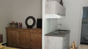 Ein gemütliches Schlafzimmer mit Bett, einem Holzschrank, einer kleinen Küchenzeile mit Spüle und einem Esstisch mit Stühlen.