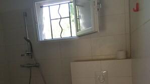 Ein Badezimmer mit Toilette, Dusche und Fenster.
