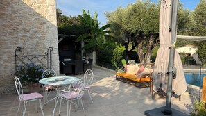 An outdoor patio with stone walls, a pool, and outdoor furniture.
