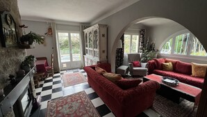 En hyggelig stue med et ternet gulv, røde sofaer og udsigt gennem et stort, hvælvet vindue.