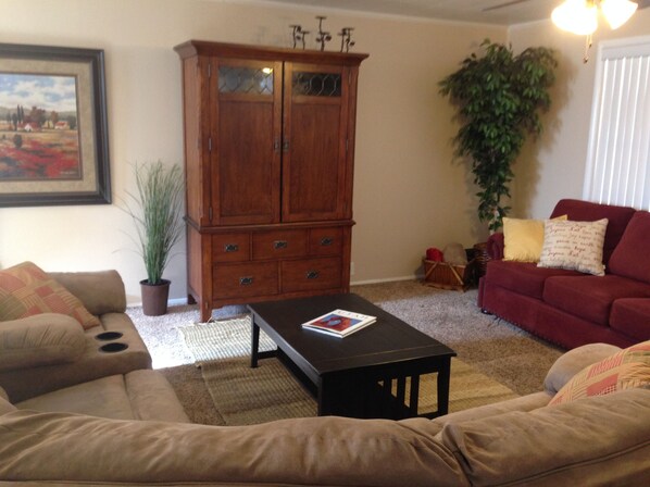 A living room with a brown sofa, a red sofa, a wooden cabinet, and a potted plant. - 2BlocksTo Southern Utah University SUU, Summer Games, Shakespeare! Sleeps 4 -15 (Cedar City)