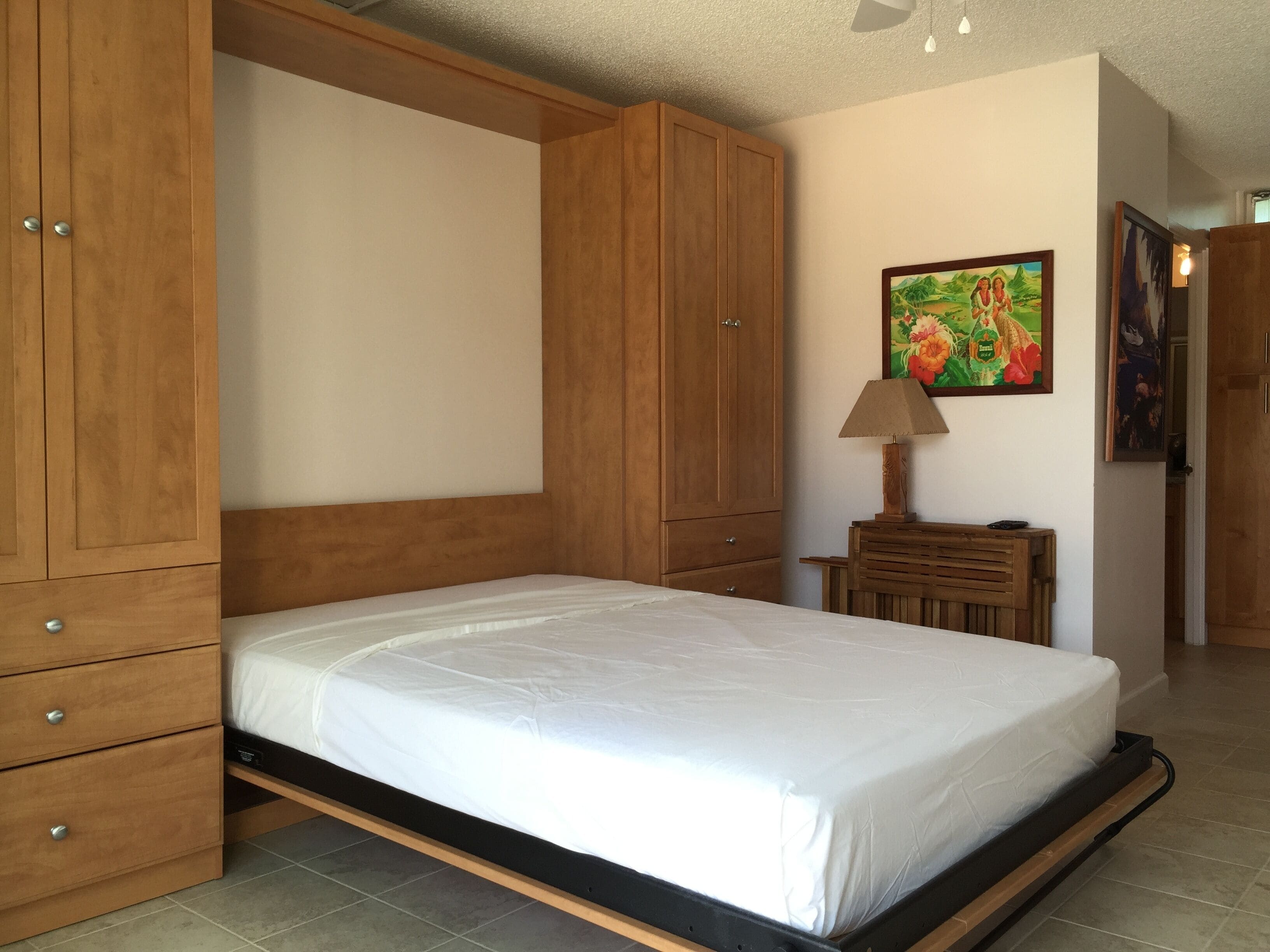 Un dormitorio con una cama, un armario de madera y una mesita de noche con lámpara.
