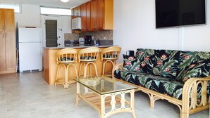 Un espacio habitable pequeño con kitchenette, un sofá y una mesa de centro de vidrio.