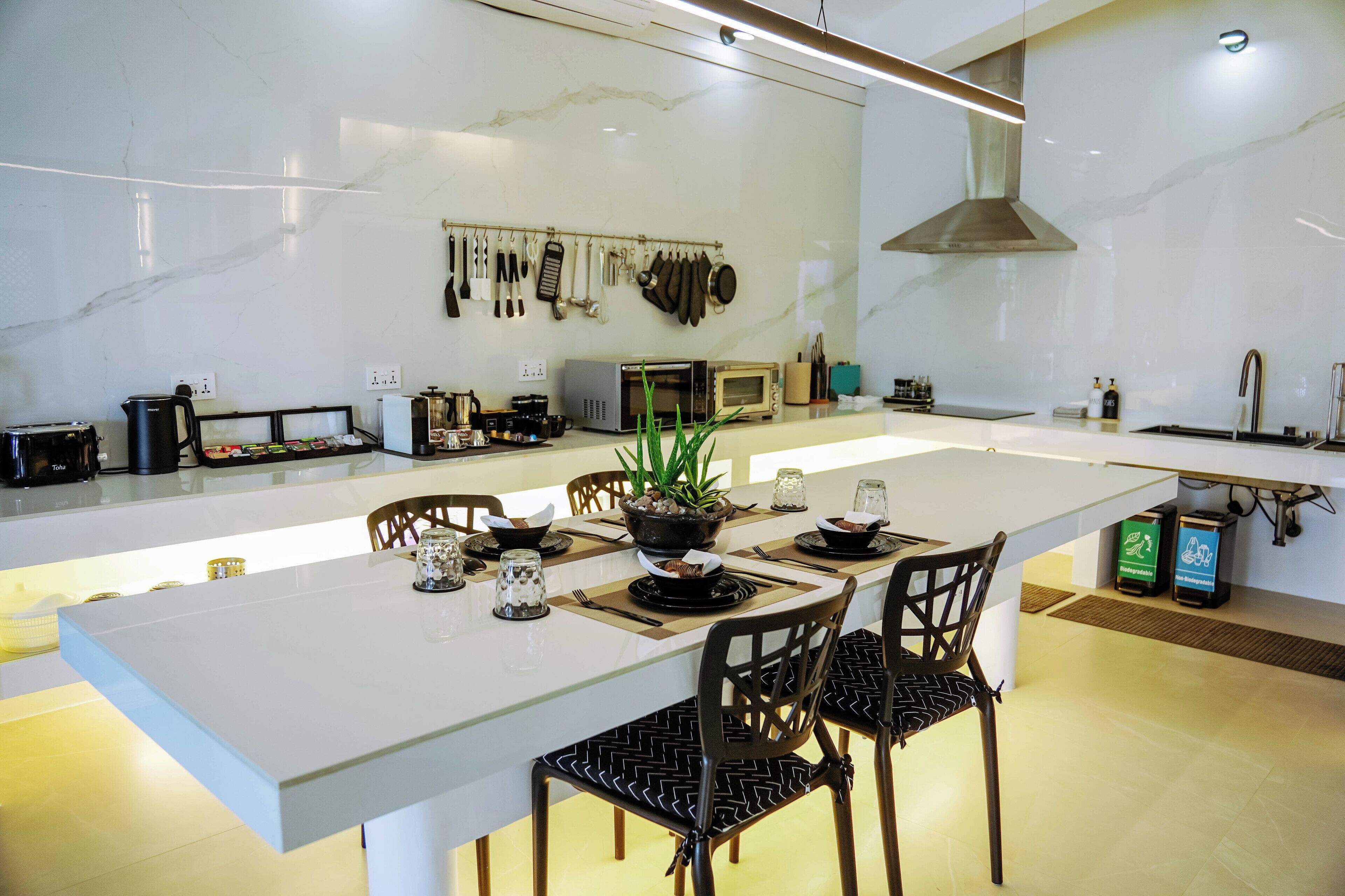 A modern kitchen with a central island, white countertops, and a variety of kitchen appliances.
