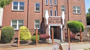 Un edificio de ladrillo rojo con varias ventanas, un cartel que dice 'Greenway Bank Place' y un letrero de 'No Estacionar'.