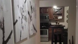 Un pasillo que conduce a una cocina con suelo de baldosas, armarios de madera y un microondas.