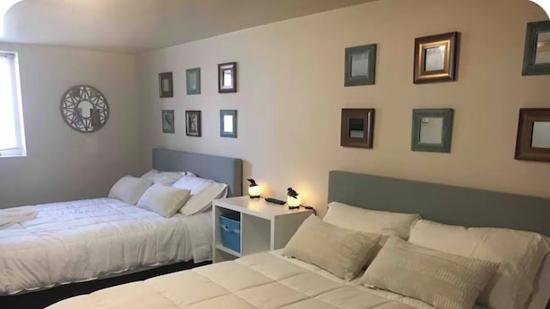 Habitación de hotel con dos camas, una mesita de noche y marcos de cuadros colgados en la pared.